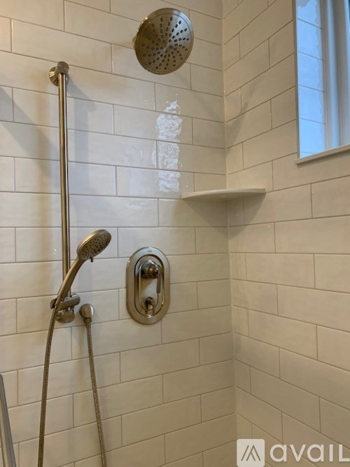 A shower with a hand held shower head and a wall mounted shower head.