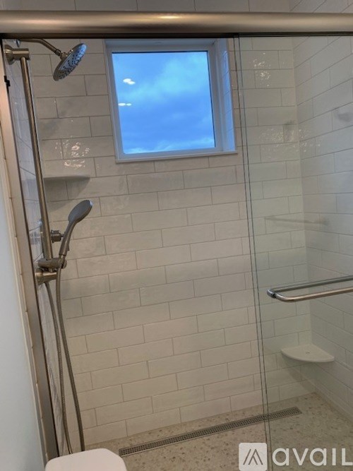 A bathroom with a glass shower door and a window.