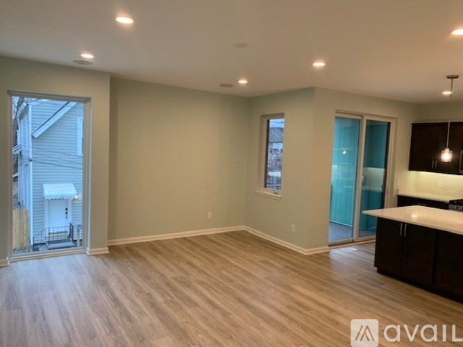 A spacious room with wooden flooring and a large window.