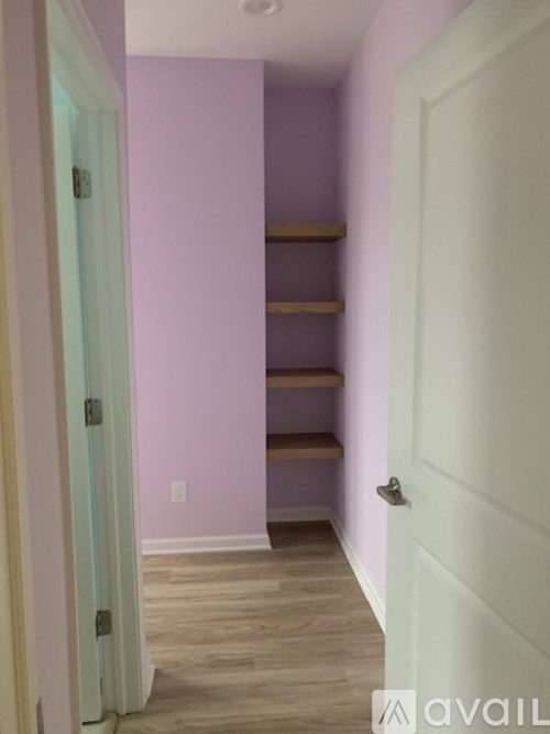 A hallway with a white door and a purple wall.