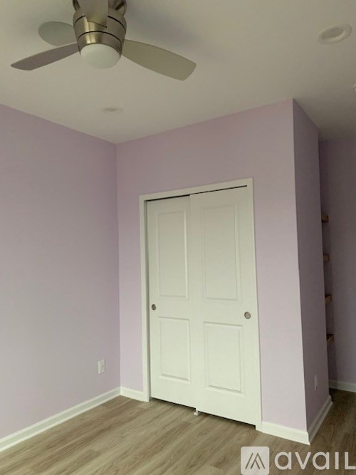 A room with a white door and a ceiling fan.