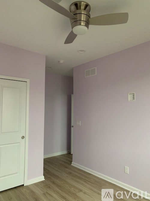 A room with a ceiling fan and a door.