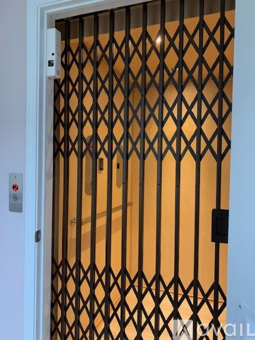 A white door with a black gate and a red button on it.