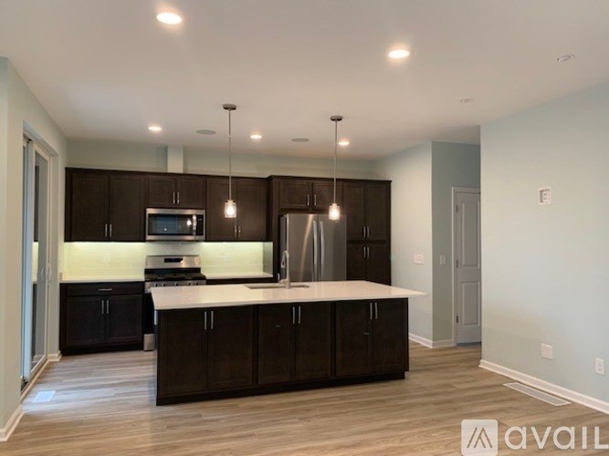 A kitchen with dark brown cabinets and a white countertop is available for rent.