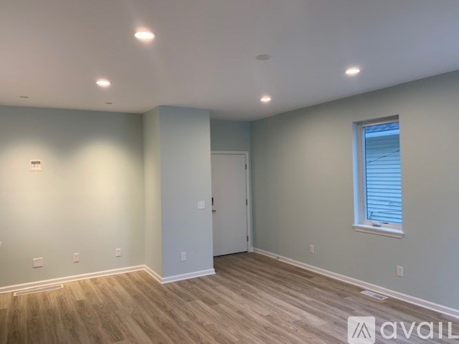A room with wooden flooring and a window with blinds.