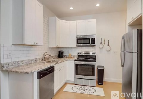 A kitchen with white cabinets and a granite countertop.