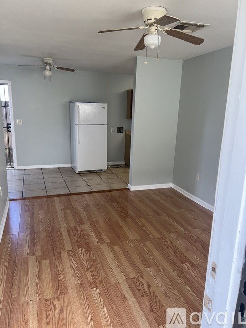 A room with a ceiling fan and a white refrigerator.