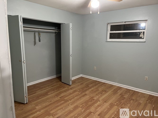 A room with a wooden floor and a grey wall with a window.