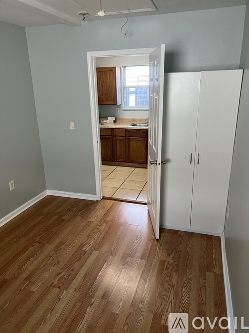 A room with a white refrigerator and wooden floors.