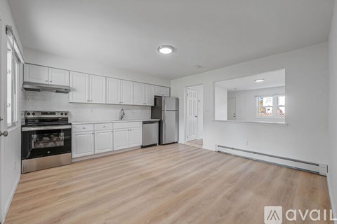A spacious kitchen with wooden flooring and white cabinetry.