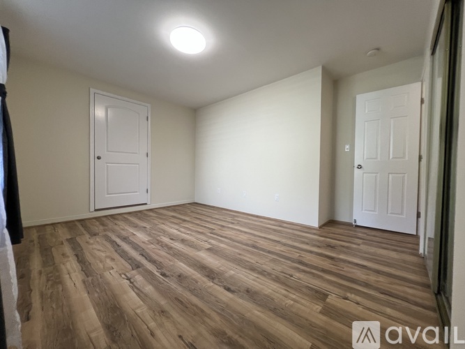 A room with wooden flooring and a large mirror on the wall.