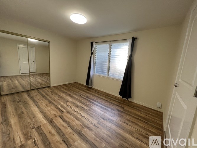 A room with wooden flooring and a large mirror on the wall.