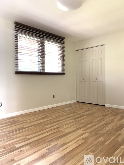 A room with wooden flooring and a window with curtains.