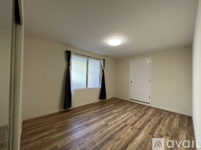 A room with wooden flooring and a window with curtains.
