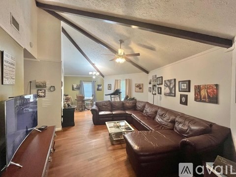 A living room with a brown leather couch and a television.