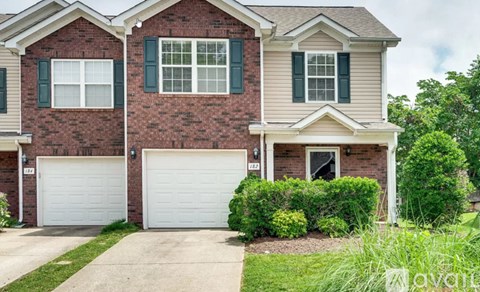 A two-story house with a brick facade and white garage doors.