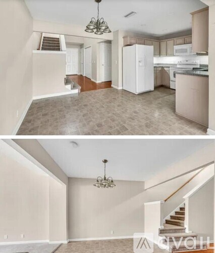 A living room with a staircase and a kitchen in the background.