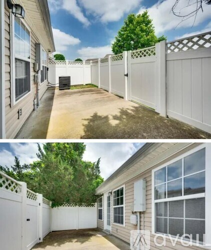 A white fence surrounds a house with a tree in the backyard.