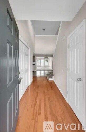 A long hallway with wooden floors and white doors.
