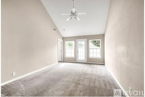 A spacious room with a ceiling fan and carpeted floor.
