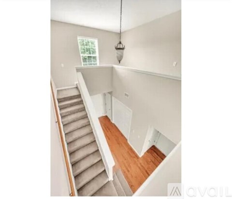A staircase with a wooden handrail and beige carpeted steps.