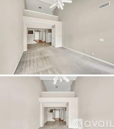 A spacious room with a ceiling fan and a hallway leading to another room.