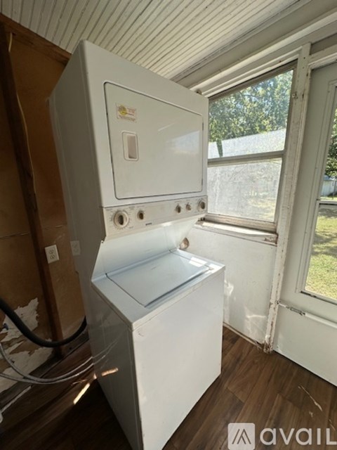 A white fridge and freezer in a room with a window.