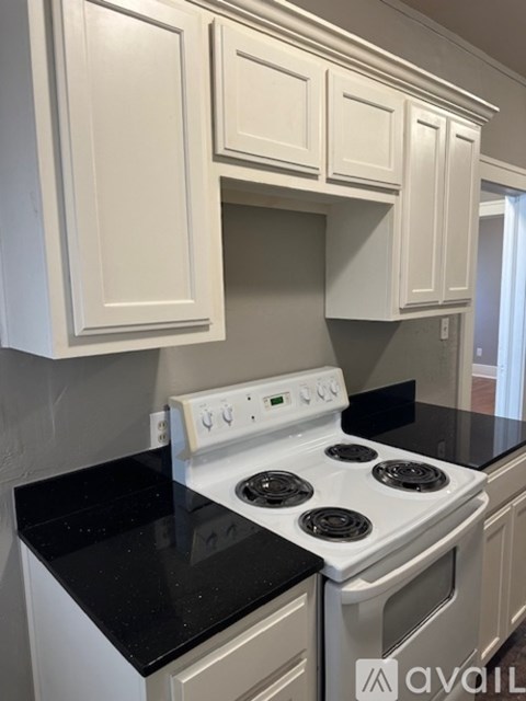 A kitchen with white cabinets and a white stove top oven.