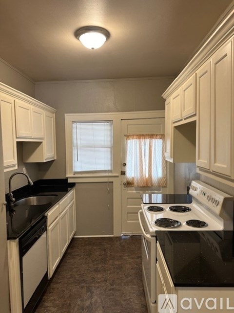 A kitchen with white cabinets and black countertops.