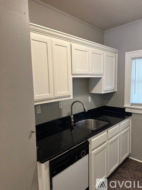 A kitchen with black countertops and white cabinets.