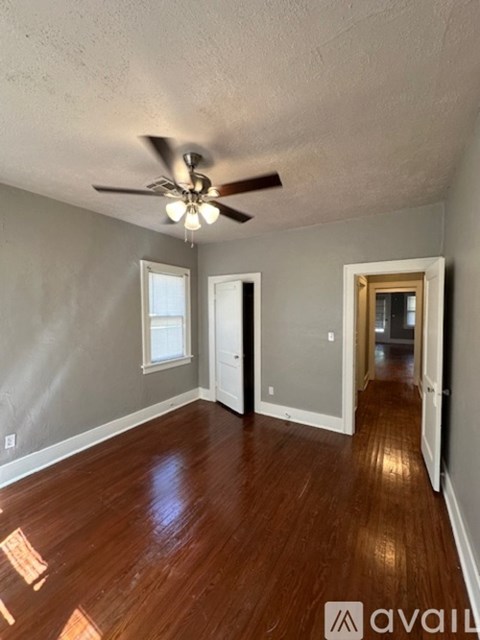 A room with a ceiling fan and wooden floors.