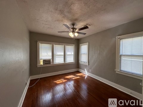 A room with a ceiling fan and wooden flooring.