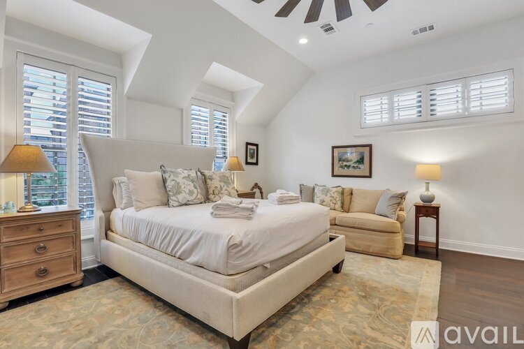 A bedroom with a large bed, a dresser, and a window with blinds.