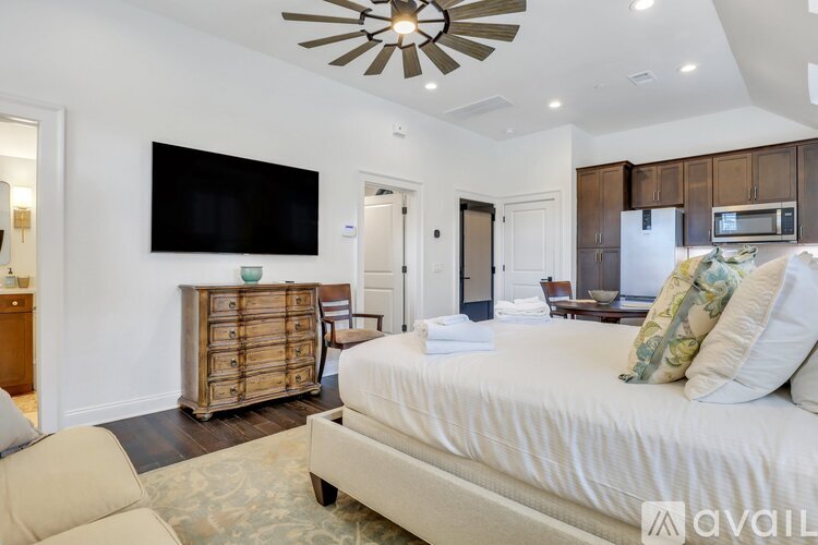 A bedroom with a large bed, a flat screen TV, and a ceiling fan.