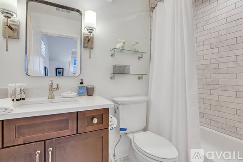 A bathroom with a toilet, sink, and mirror.