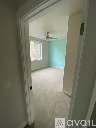 A room with a ceiling fan and a door leading to another room.