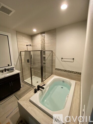 A modern bathroom with a glass shower stall and a jacuzzi tub.