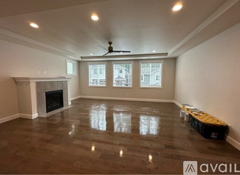 A spacious room with a fireplace and a ceiling fan.