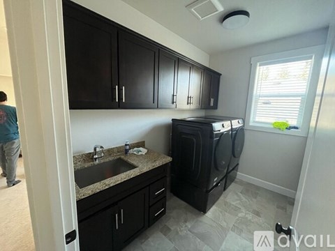 A kitchen with black cabinets and a washer and dryer built in.
