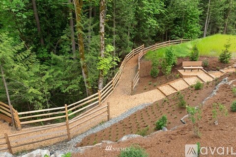A wooden fence runs along a hillside with a forest in the background.