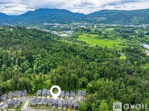 A bird's eye view of a residential area surrounded by greenery and mountains.