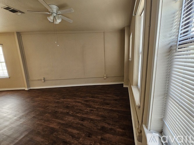 A room with a ceiling fan and wooden flooring.