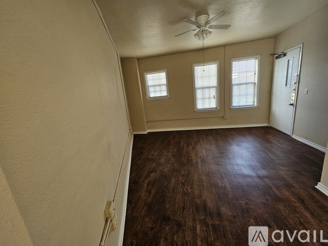 A room with a ceiling fan and three windows.