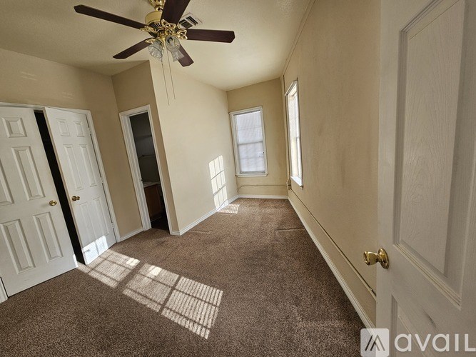 A room with a ceiling fan and carpeted floor.
