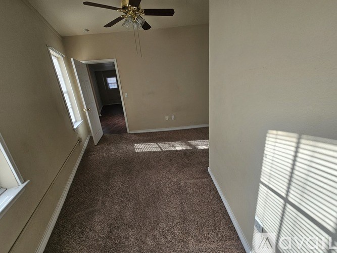 A room with a ceiling fan and carpeted floor.
