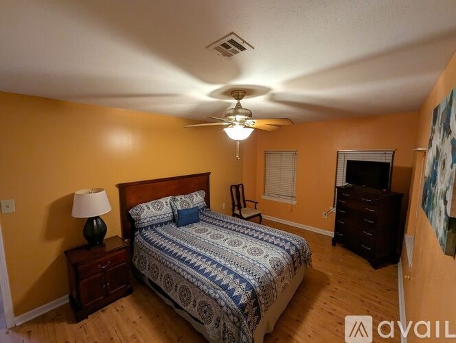 A bedroom with a bed, dresser, and ceiling fan.