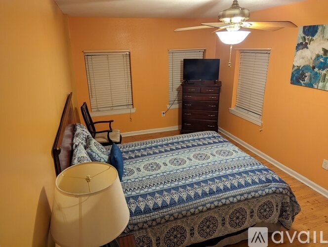 A bedroom with a bed, dresser, and a ceiling fan.