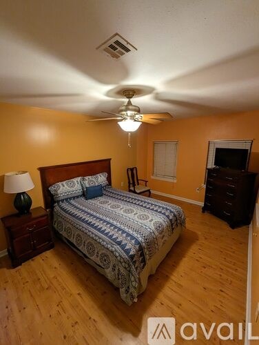 A bedroom with a bed, dresser, and ceiling fan.