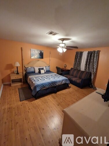 A bedroom with a bed, a couch, and a ceiling fan.