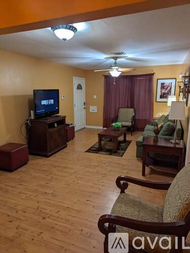 A living room with a television, two chairs, and a table.